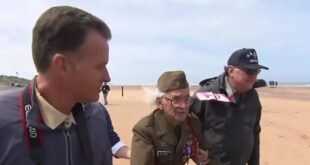 WWII veteran Robert Blatnik walking on Omaha Beach in Normandy in 2013