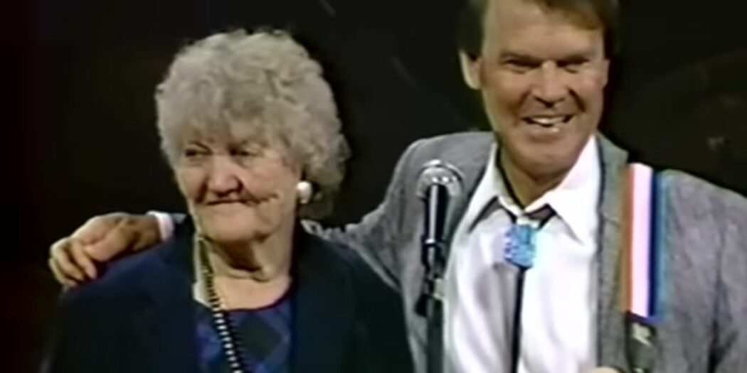Glen Campbell with his arm around his mother Carrie as they sing together on stage