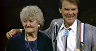 Glen Campbell with his arm around his mother Carrie as they sing together on stage