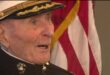 104-year-old Marine veteran Major Bill White in his dress cap next to an American flag