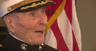104-year-old Marine veteran Major Bill White in his dress cap next to an American flag