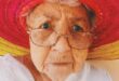An older woman with glasses and a red sun hat