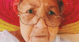 An older woman with glasses and a red sun hat