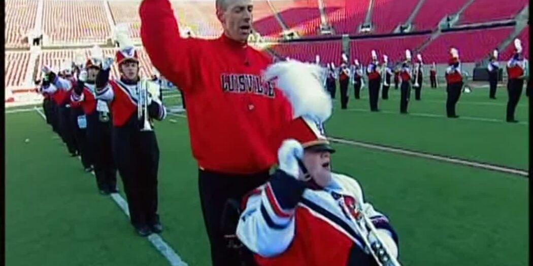 Patrick John Hughes pushes his son Patrick Henry Hughes in his wheelchair with the Louisville marching band