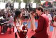 Tom Holland kneeling beside a little girl holding a microphone at a Spider-Man fan event in Paris