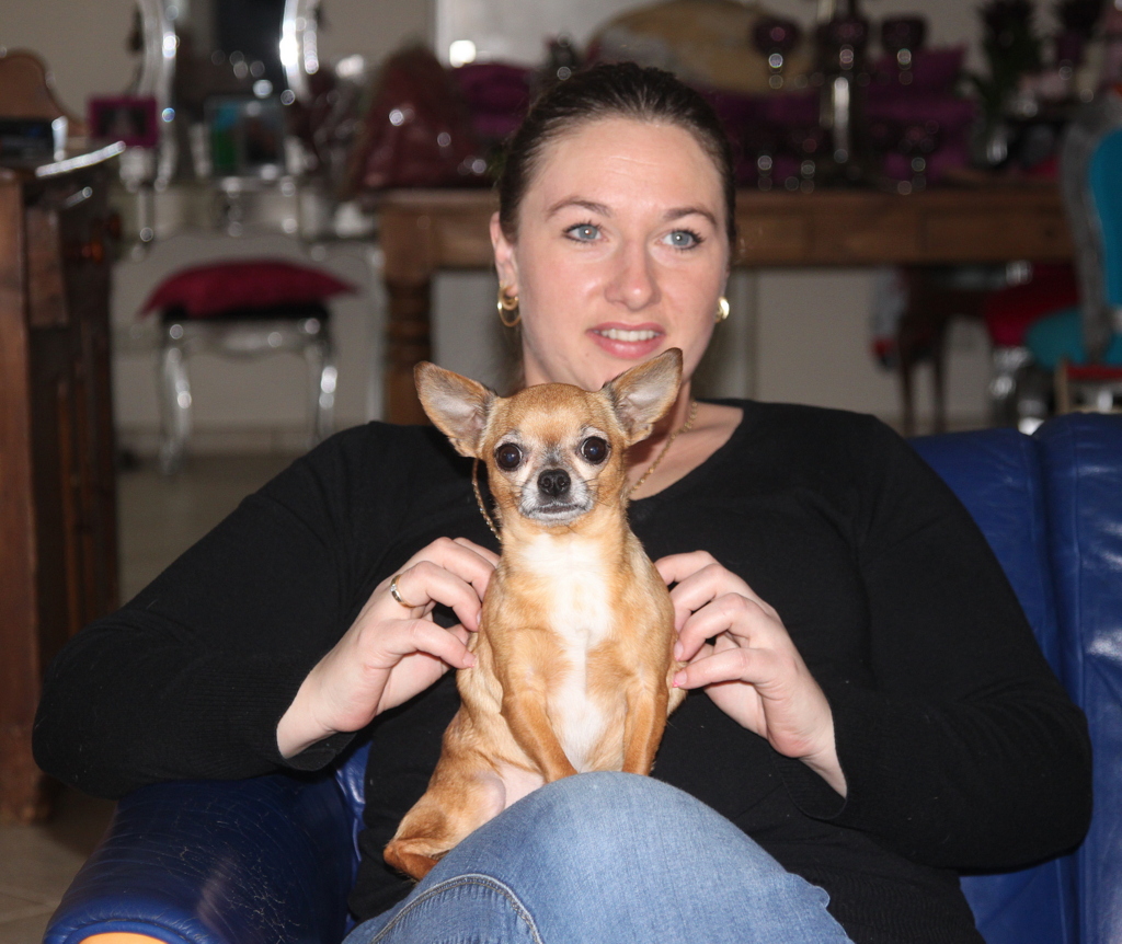 A smiling woman holding a small Chihuahua